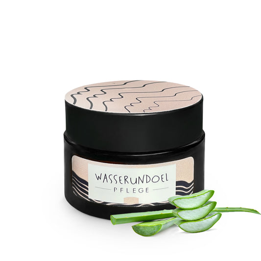 Tiegel mit feuchtigkeitsspendender Aloe-Vera-Creme von wasserundoel und frischen Aloe-Vera-Blättern